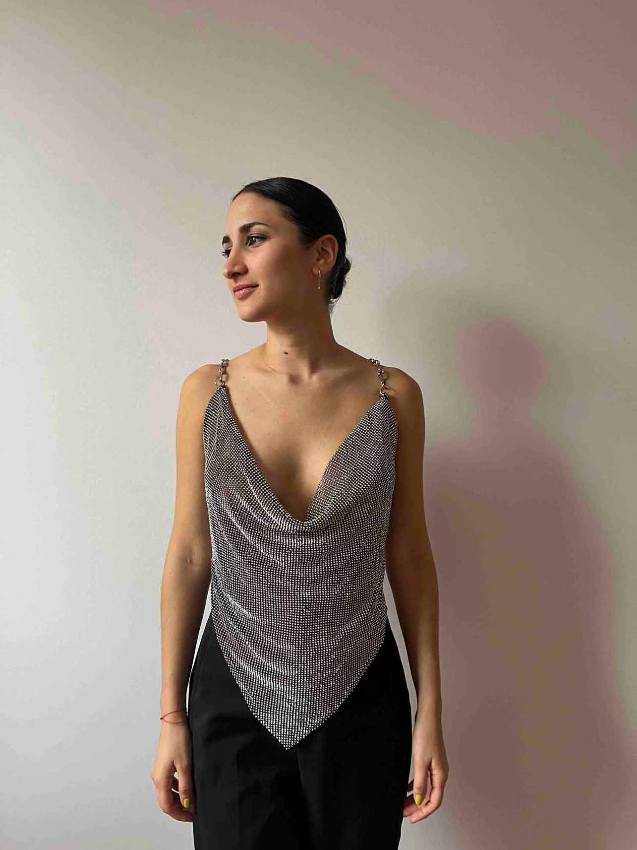 Model wears a chainmail crystal crop top in black and silver. Embellished cowl neckline top for party clothing and rave festival outfits.