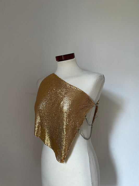 Model wearing a chainmail metal mesh top in color Gold. One shoulder with silver chains on the side.